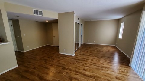 A room with wooden flooring and a window on the right side.